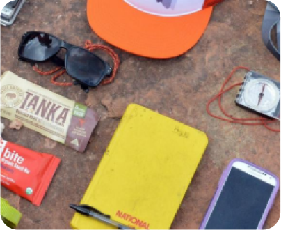 image of elements of a person such as a notebook, chocolates, a cell phone, a compass and a cap